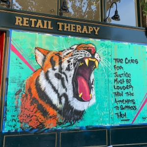 Mural of a tiger painted onto boards covering the windows of Retail Therapy.