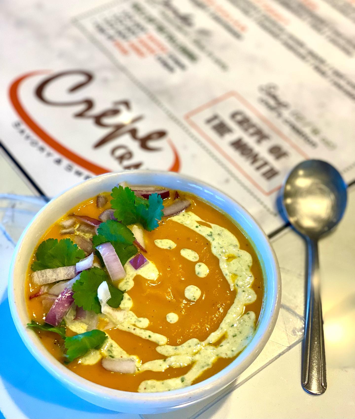 A bowl of soup sitting on a Crepe Crazy menu