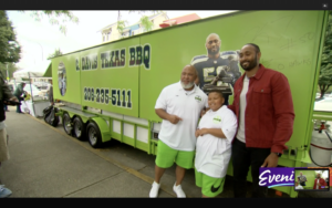 photo of KJ Wright and C. Davis of C. Davis Texas BBQ standing for a photo in front of the lime green BBQ truck with the KJ Wright decal behind them.