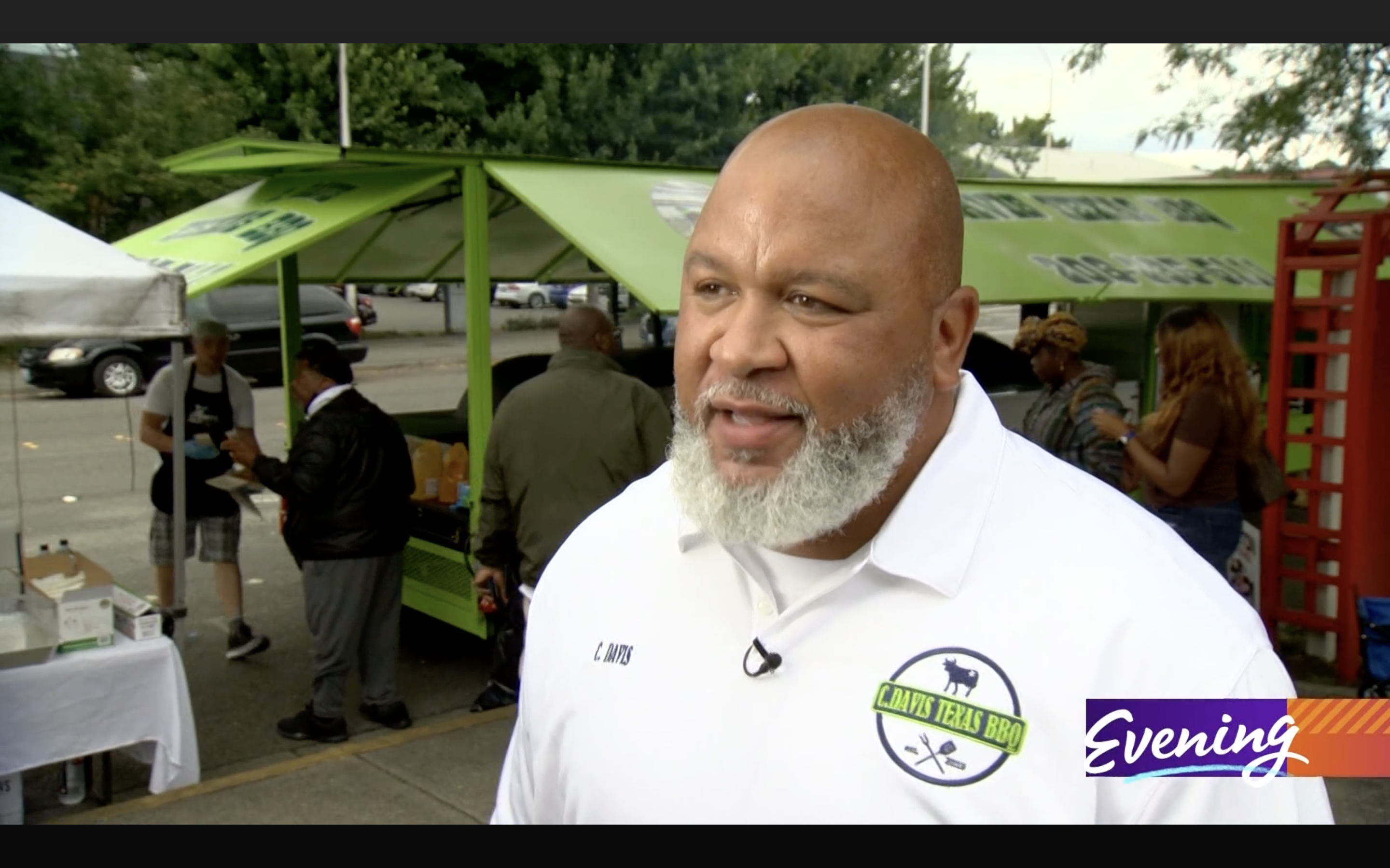 photo of C. Davis of C. Davis Texas BBQ wearing a white polo with his business logo, being interviewed by King5 news