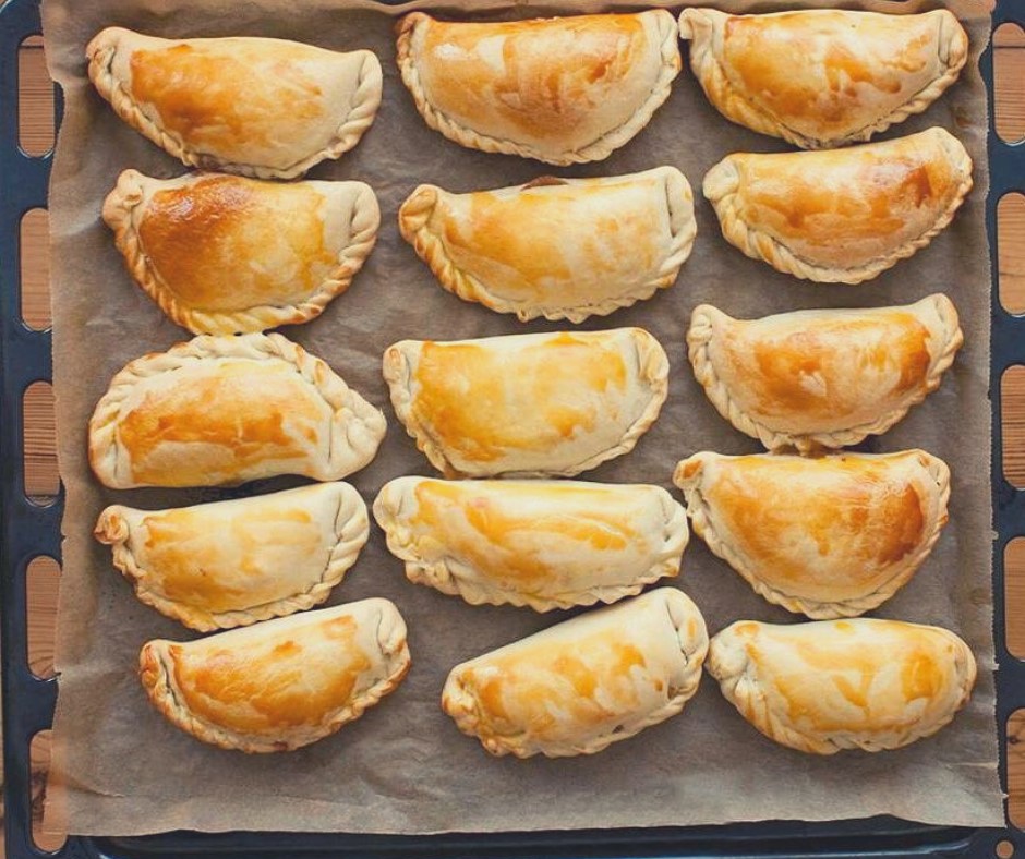 a baking sheet of freshly baked golden brown empanadas