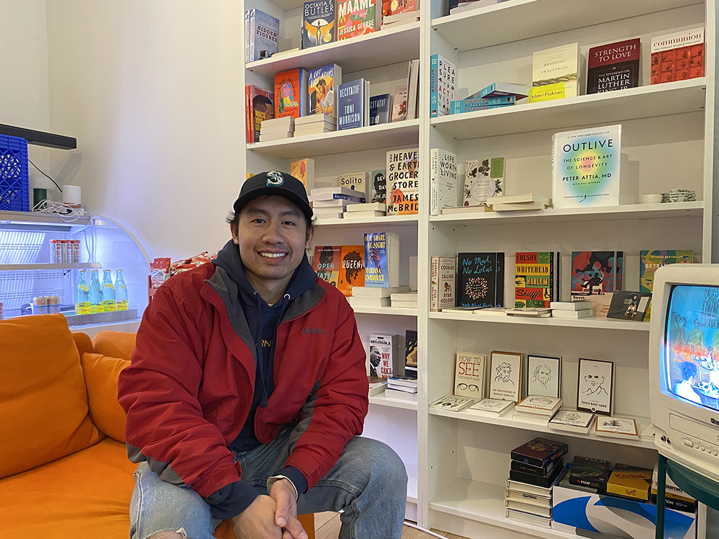 Mam's Books owner Sokha Danh sitting in front of a bookshelf