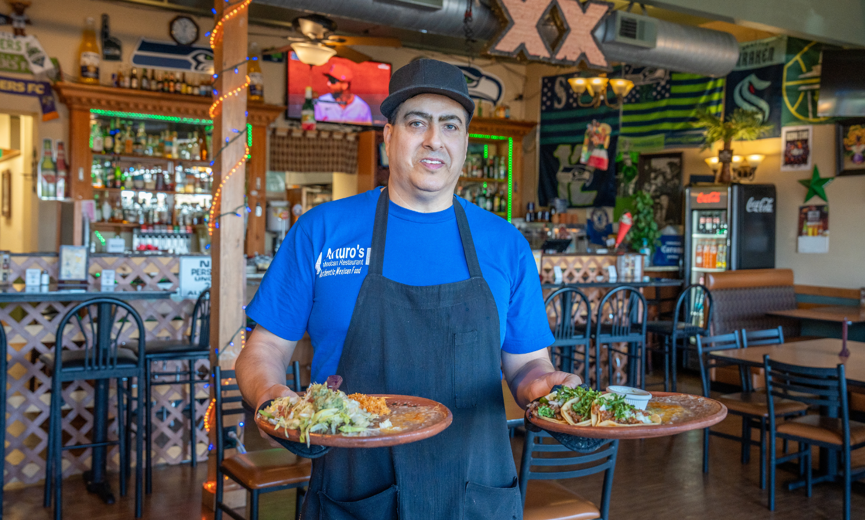 Arturo's Mexican Restaurant owner holding two plates of food