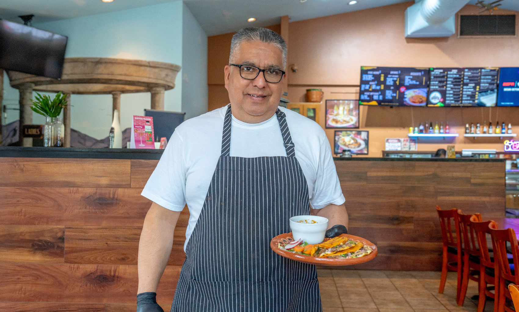 Birrieria Grumpy's owner holding a plate of food.